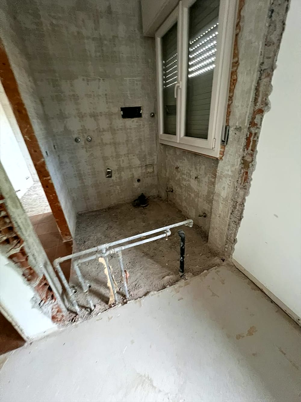 Ristrutturazione bagno: piccolo ambiente con rivestimento a piastrelle bianche e finestra