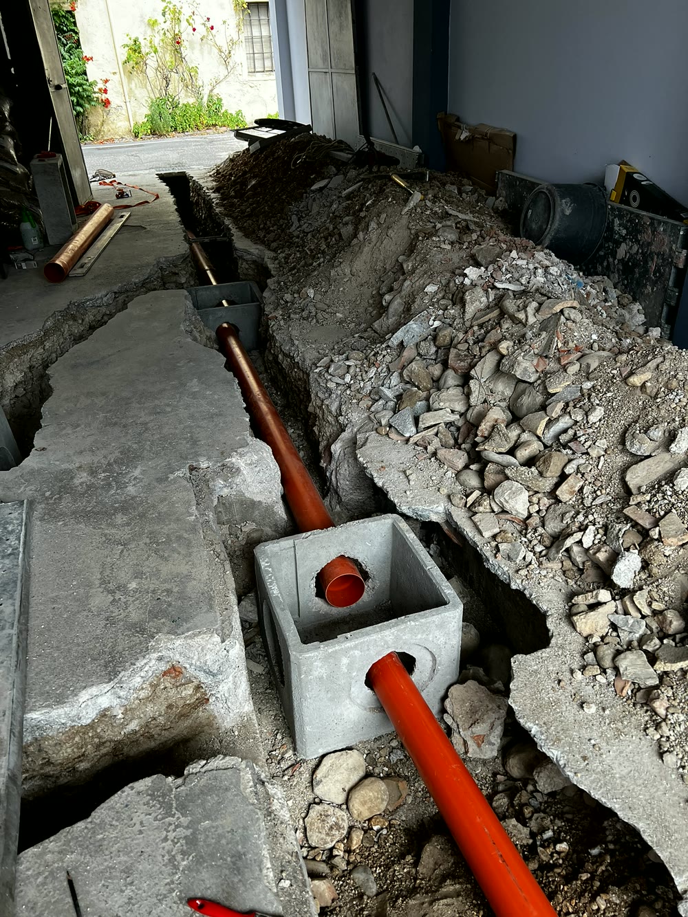 Impianti elettrici e idraulici: scavo con tubo di scarico arancione e pozzetto