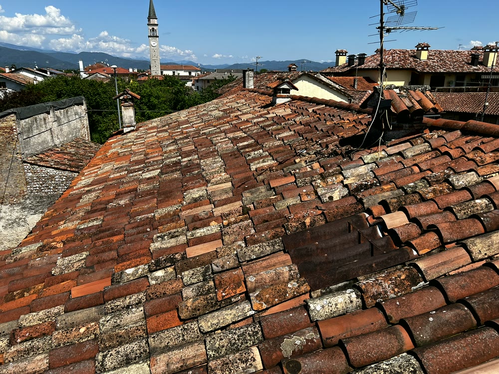 Tetti e coperture: tetto spiovente in coppi già posato con vista sul campanile del paese